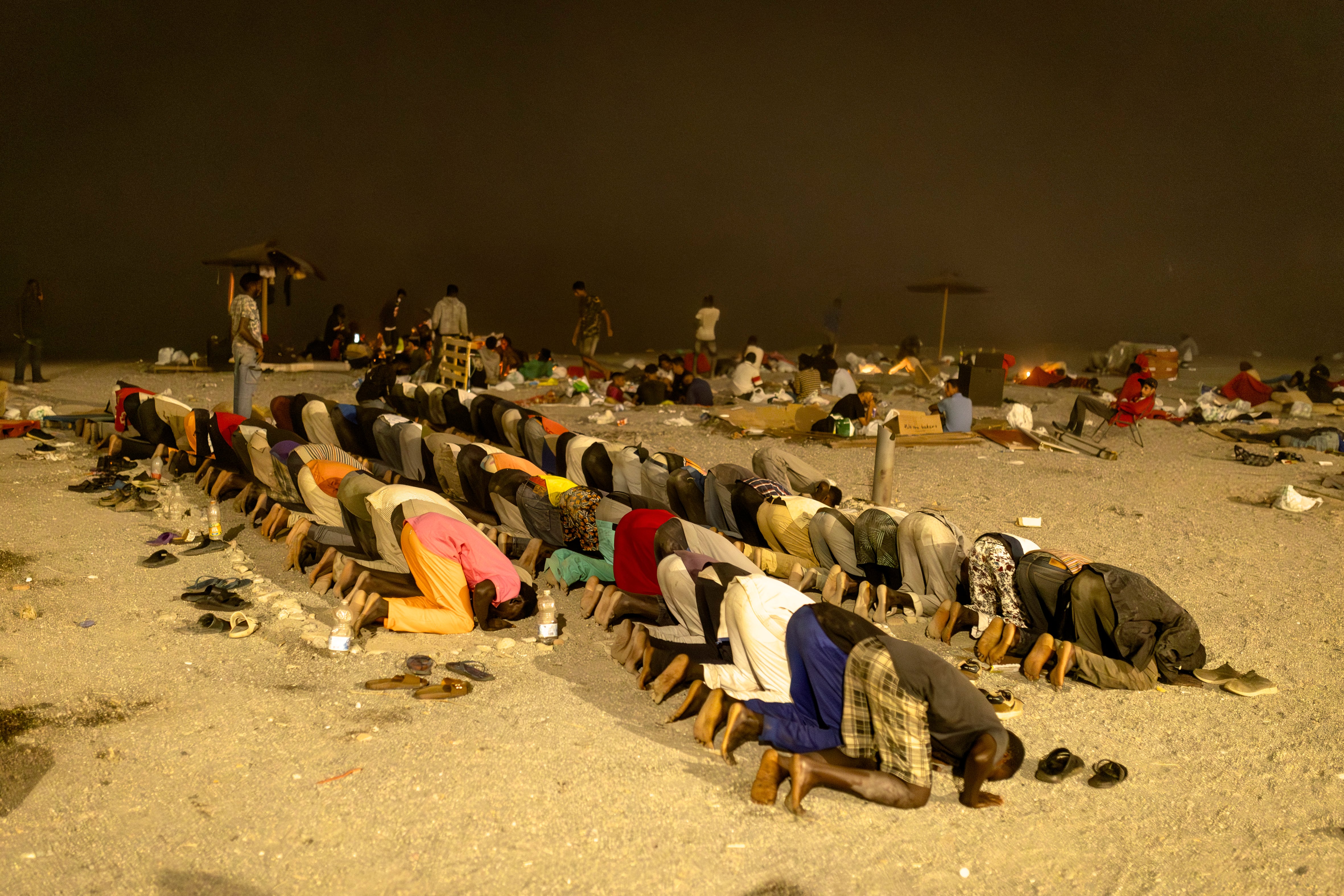 Un grupo de inmigrantes rezan en la playa de El Trampolín, la madrugada del sábado 8 de agosto. 
