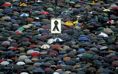 Un gran lazo negro domina sobre los paraguas en la plaza de Colón de Madrid.