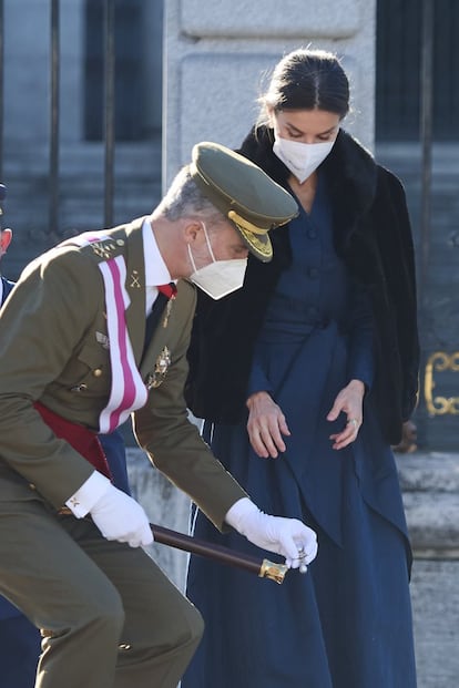 El rey Felipe VI recoge del suelo un broche de la reina Letizia, durante el desfile de la Pascua Militar.