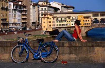 Una viajera y su bici en el Ponte San Trinita de Florencia, con el Ponte Vecchio al fondo.