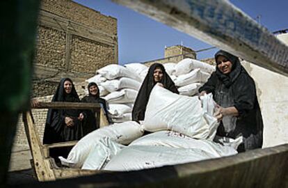 Varias mujeres iraquíes sonríen mientras recogen su ración mensual de harina en Bagdad. PLANO GENERAL - ESCENA