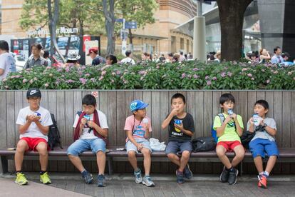 Un grupo de niños come helados en un banco, en Roppongi, Tokio, el 22 de julio de 2018. 