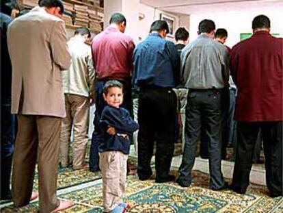 Un niño reza junto a su padre en el oratorio de la avenida de la Meridiana de Barcelona.