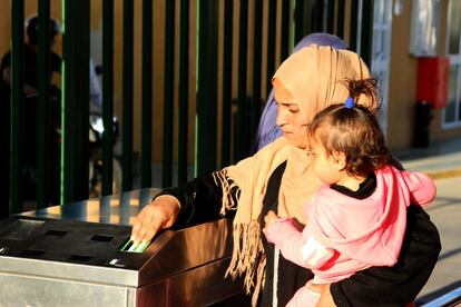 Una mujer siria y su bebe pasan su tarjeta de residente en el CETI para acceder al centro.