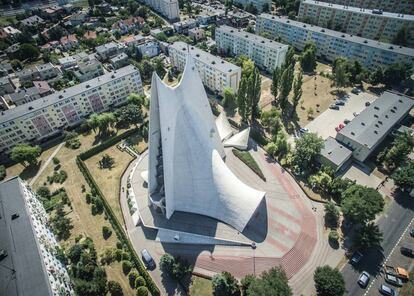 <strong>La sábana de hormigón</strong>. Iglesia de la Divina Gracia, en Kalisz (1977-1993, aunque su diseño es de los años cincuenta). Los arquitectos Jerzy Kuźmienko y Andrzej Fajans tenían tan solo 27 y 23 años cuando diseñaron este templo de forma abstracta que parece cubierto por una tela blanca que ondea en la parte inferior, gracias a la cubierta maciza de hormigón reforzado de una sola capa. Se trata de un estilo que ya se había utilizado internacionalmente en los 50, pero en pequeñas dimensiones. La de la iglesia de Kalisz tiene una superficie de 1.000 metros cuadrados y una altura de 45 metros, con una forma ondeada iregular y una capa muy fina. De ahí que el arquitecto e historiador Maciej Czarnecki comparara en 2012 en las páginas de 'Architektura' este trabajo con el de maestros como Oscar Niemeyer y Félix Candela. |