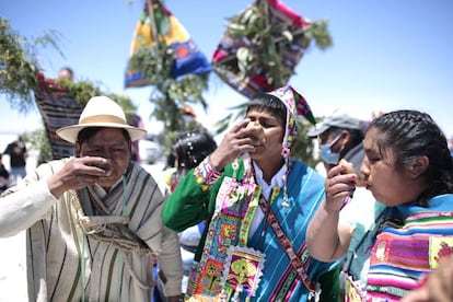 Uyuni, Bolivia, 2 de octubre de 2021: Paola, Samuel (centro) y David, padrino de boda, beben chicha boliviana —bebida artesanal de maíz fermentado— después del matrimonio civil en el Salar de Uyuni. Los tres llevan trajes tradicionales de esta zona del departamento de Potosí.