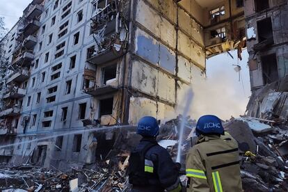 Dos bomberos trabajan para extinguir un fuego en un edificio residencial dañado por un misil ruso, este domingo en Zaporiyia.