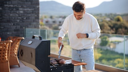 Un hombre preparando carne en una barbacoa.