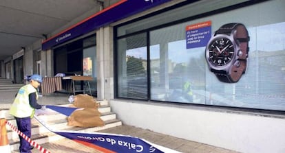 Un trabajador cambia los carteles de Caixa Girona.