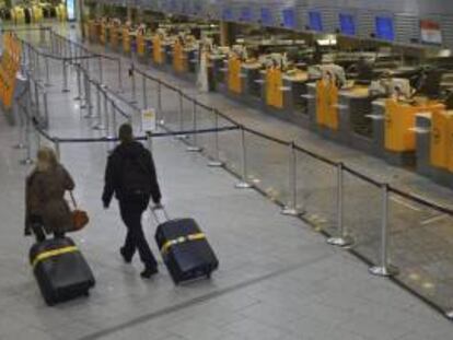 Dos pasajeros caminan junto a las mesas de facturación vacías de Lufthansa en el aeropuerto de Fráncfort (Alemania). EFE/Archivo