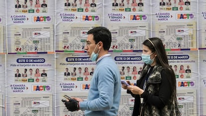 Una pareja pasa frente a una pancarta con información sobre las elecciones en Bogotá, el 10 de marzo.