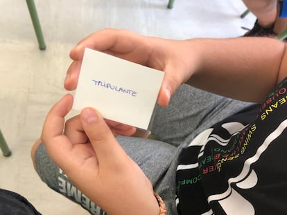 Un alumno sujeta una tarjeta del juego 'Among us' en clase.