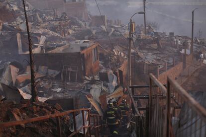 El siniestro, cuyas causas se desconocen por el momento, se inició en una zona de matorrales y eucaliptos, y produjo una extensa columna de humo visible a decenas de kilómetros de distancia. En la imagen, algunos bomberos examinan las viviendas quemadas.