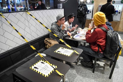 Unos jóvenes almuerzan en un restaurante de comida rápida con el aforo reducido.
