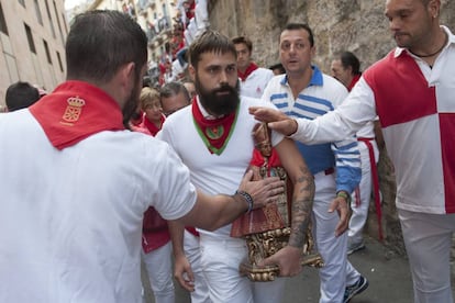 Corredores tocan la figura de San Fermín momentos antes del quinto encierro.