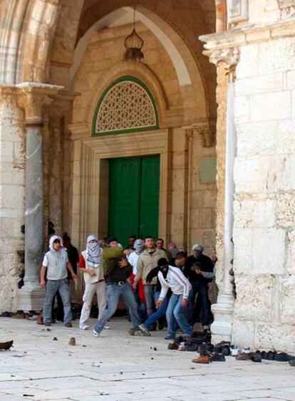 Unos palestinos arrojan piedras a los policías antidisturbios dentro del recinto de la mezquita de Al Aqsa, en la Explanada.