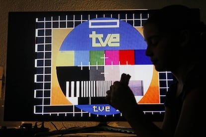 Una niña merienda frente a una televisión con una carta de ajuste de TVE.