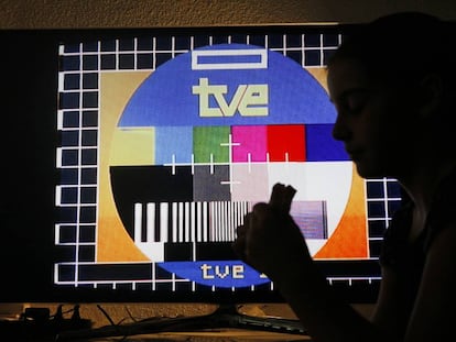 Una niña merienda frente a una televisión con una carta de ajuste de TVE.