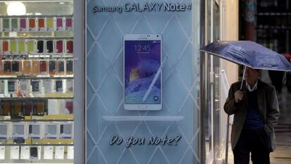 Un hombre junto a una tienda con un anuncio del Samsung Galaxy