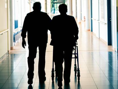 Una pareja de personas mayores camina con un andador. 