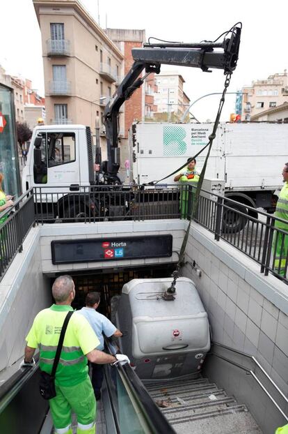 Retirada de un contenedor de basura que bloqueaba la entrada de la estación del Metro de Horta, este viernes, en Barcelona.