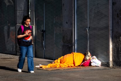 Una mujer pasa por delante de una persona sin hogar en los alrededores de la Plaza Mayor de Madrid.
