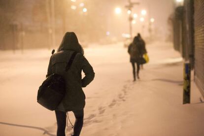 Pedestres caminham por uma rua nevada em Nova York.