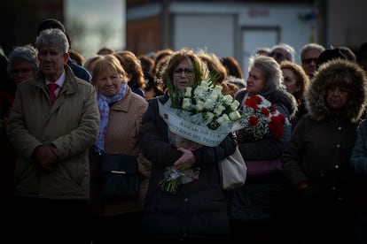 Varias personas con ramos de flores acuden al acto en recuerdo de las víctimas de los atentados del 11-M, celebrado este lunes frente a la estación de Cercanías de Santa Eugenia, Madrid.