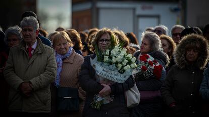 Varias personas con ramos de flores acuden al acto en recuerdo de las víctimas de los atentados del 11-M, celebrado este lunes frente a la estación de Cercanías de Santa Eugenia, Madrid.