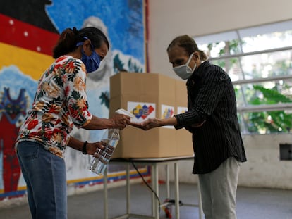 Una mujer ofrece gel antibacterial en un colegio electoral de Caracas, este domingo durante la celebración de elecciones legislativas.