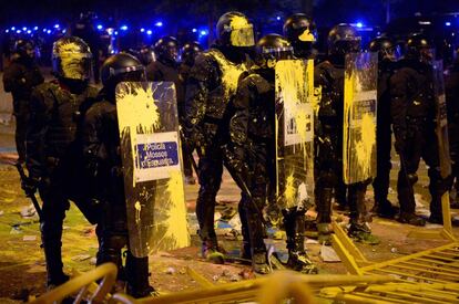 Varios Mossos cubiertos de pintura mantienen su posición ante los manifestantes que se han concentrado frente a la Subdelegación del Gobierno en Girona.