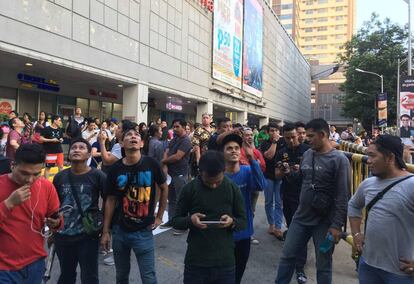 Varios ciudadanos evacuados de un centro comercial en Manila tras el terremoto. 