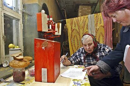 Un miembro de la comisión electoral ayuda a la anciana Ekaterina Yaskevich a votar en su casa de Damashany.