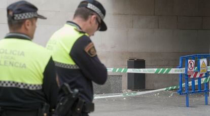 Dos policías junto a la zona acordonada tras caer un trozo de la fachada de la Ciudad de la Justicia de Valencia.