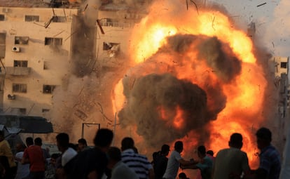 Un grupo de palestinos ante la bola de fuego provocada por un ataque israelí contra un edificio de viviendas en Ciudad de Gaza, este sábado.