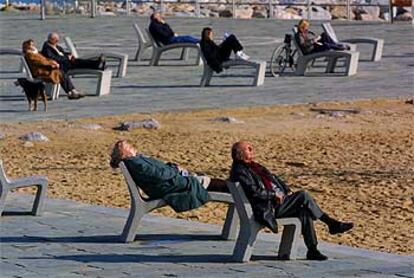 Un grupo de ciudadanos aguarda la nieve en la playa de Nova Icària, bañada por un cálido sol de invierno.