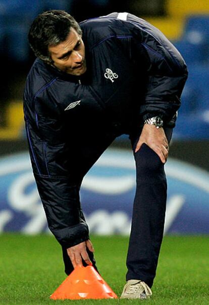José Mourinho se agacha para recoger un cono.