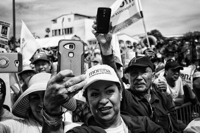 Una mujer toma fotografías con su teléfono celular a la llegada de Andrés Manuel a Playas de Rosarito.