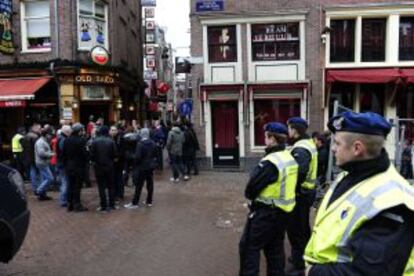 Oficiales holandeses vigilan a un grupo de aficionados del Manchester United que hoy se enfrenta al Ajax.