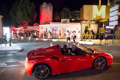 Un Ferrari circula frente a la discoteca Mirage, cerrada, y el Sunset Café, en Puerto Banús (Marbella).