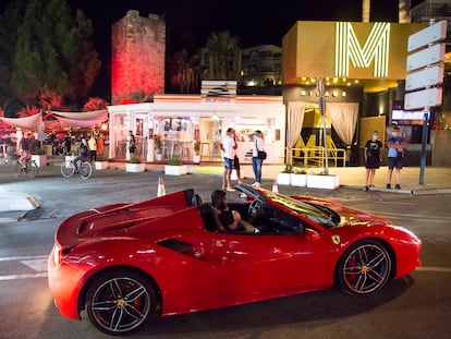 Un Ferrari circula frente a la discoteca Mirage, cerrada, y el Sunset Café, en Puerto Banús (Marbella).