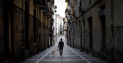 Un joven pasea a su perro por una calle desierta del casco histórico de Pamplona, este sábado.