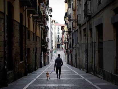 Un joven pasea a su perro por una calle desierta del casco histórico de Pamplona, este sábado.