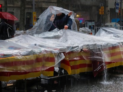 Vendedores de un puesto de libros intentan proteger su expositor del granizo caído en Barcelona.