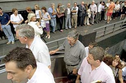 La gente sale del metro mientras otras personas hacen cola a las puertas de un banco en Buenos Aires.