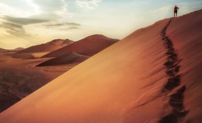 Un turista contempla el amanecer desde la Duna 45 de Sossusvlei, en el desierto del Namib (Namibia).