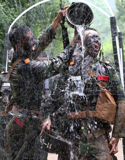 Dos soldados surcoreanos se refrescan echándose un cubo de agua durante un entrenamiento militar, en Nonsan, Corea del Sur.