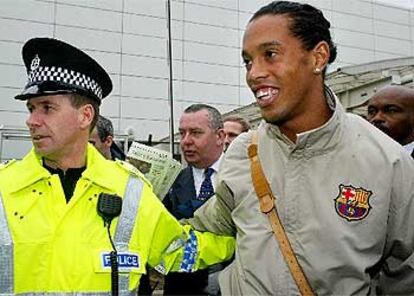 El jugador del Barcelona Ronaldinho es escoltado por la policía a su llegada hoy al aeropuerto de Glasgow.