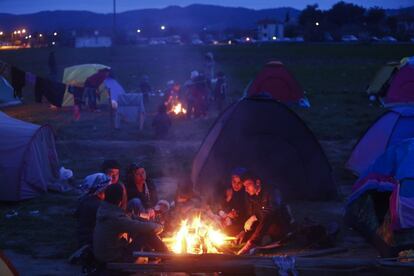 Biberones de noche. dos madres dan el biberón a sus bebés al rederdor del fuego en el campamento de Idomeni.