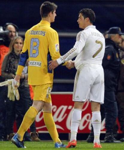Cristiano, con el balón del partido bajo la camiseta, saluda a Courtois al término del derbi
